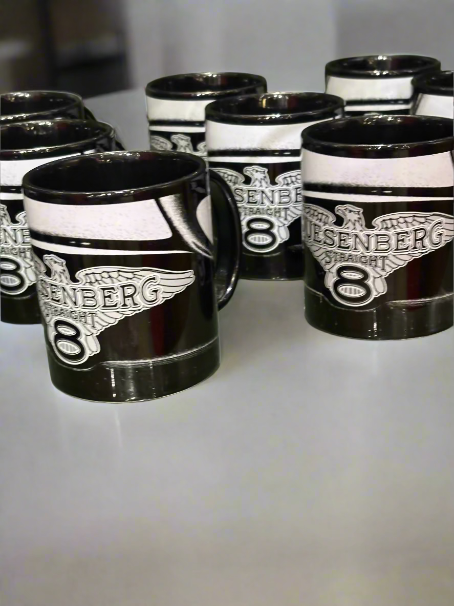 Black and white mugs with 'Duesenberg 8' branding on a reflective surface.